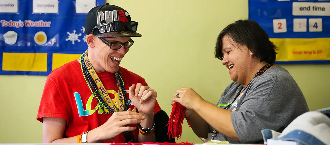 A LARC participant and instructor laughing together during a craft activity