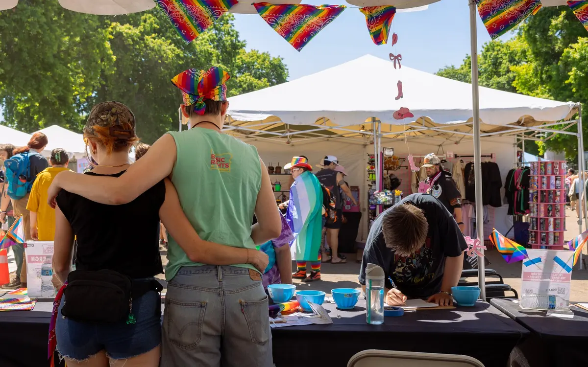 Basic Rights Oregon volunteers and attendees interacting at an outdoor Pride festival booth