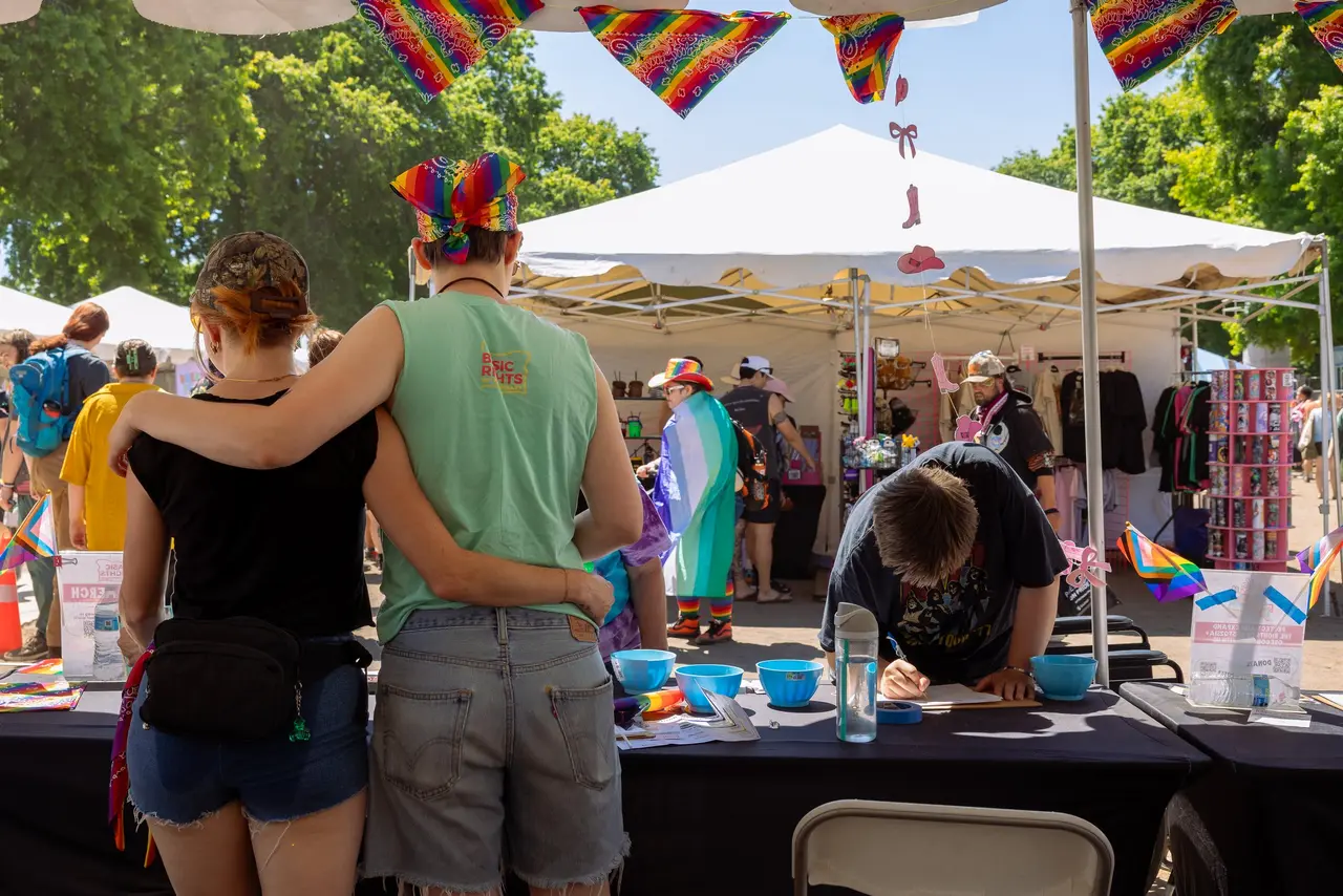 Basic Rights Oregon volunteers and attendees interacting at an outdoor Pride festival booth