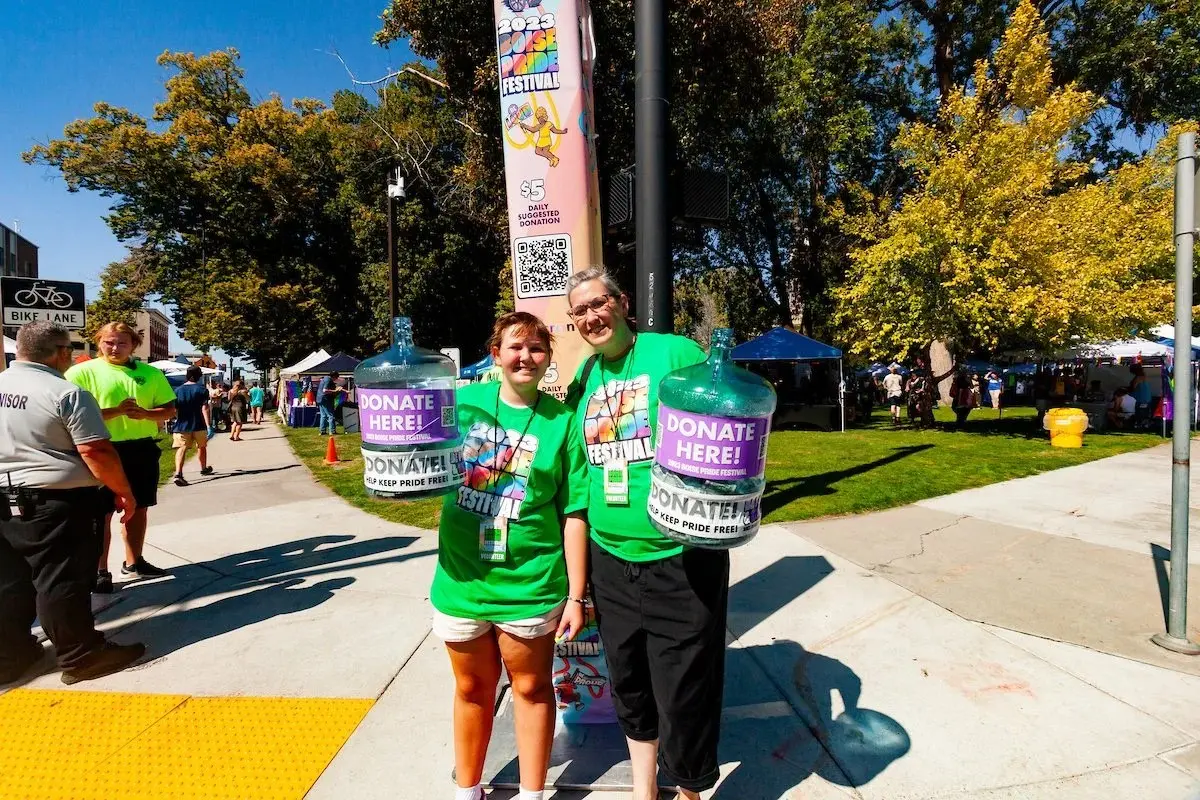 Boise Pride volunteers in green shirts holding donation buckets at the festival