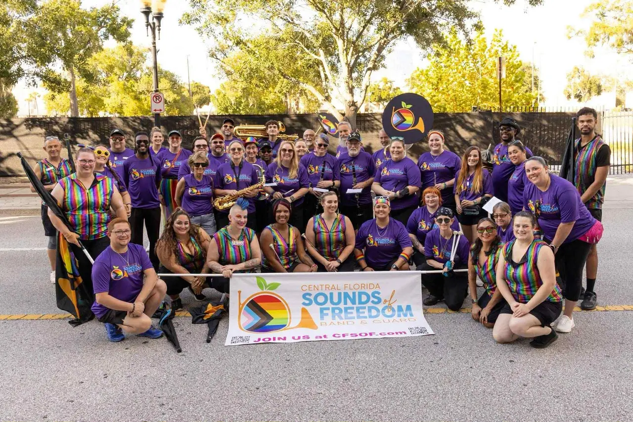 CFSOF marching band and color guard members in purple shirts with their banner at Come Out With Pride 2025