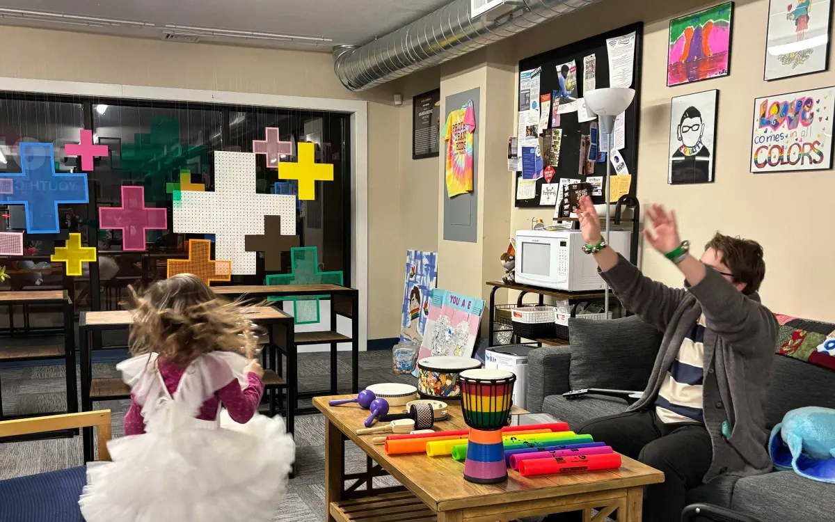 Children and adult facilitators engaging in music therapy with colorful percussion instruments in the youth center living room