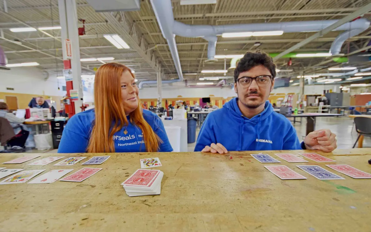 Staff member and participant playing a card game together in a day center workshop room
