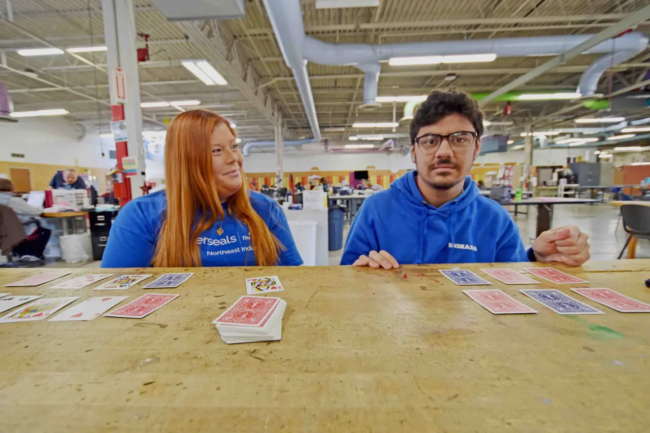 Staff member and participant playing a card game together in a day center workshop room