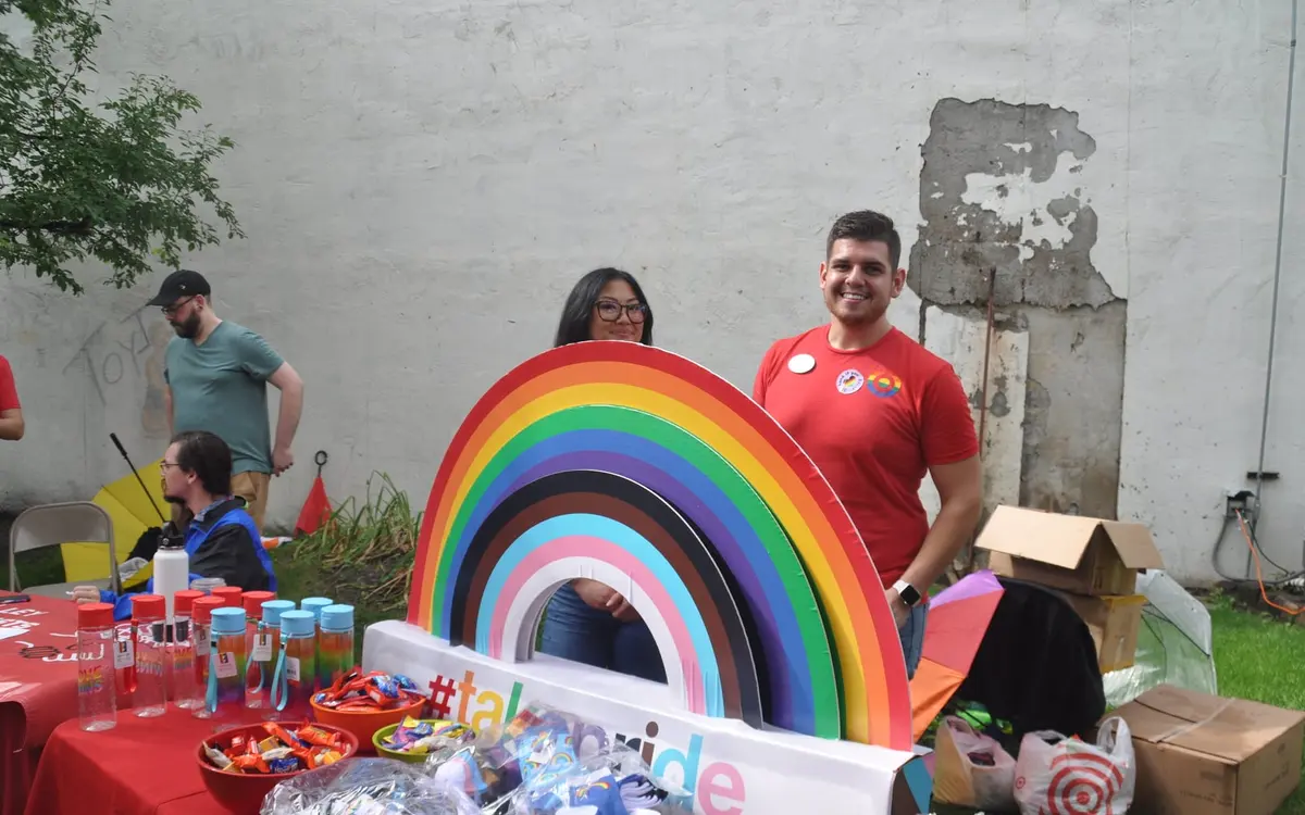 Volunteers smiling at the Grand Forks Pride community booth with a rainbow display