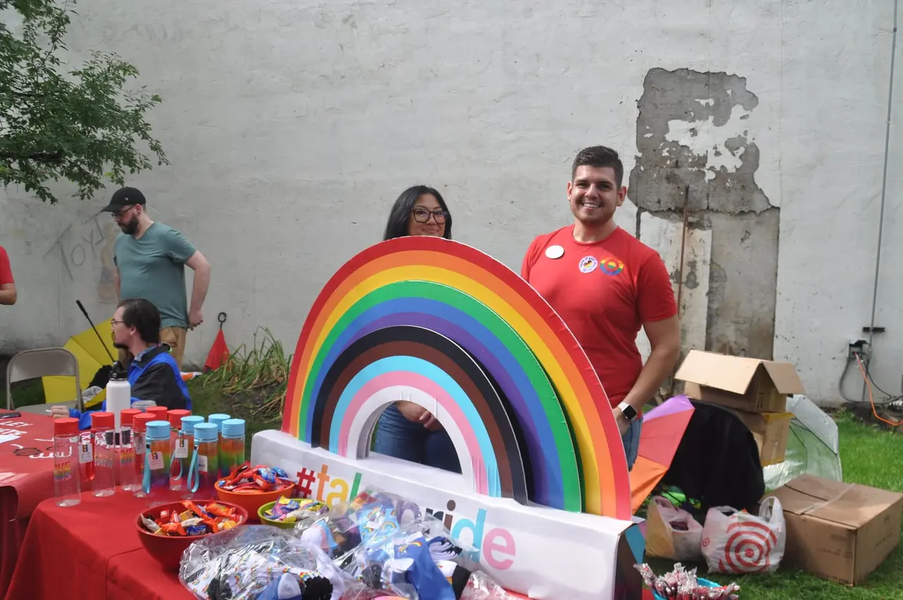 Volunteers smiling at the Grand Forks Pride community booth with a rainbow display
