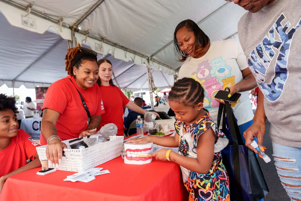 Volunteers helping children at a dental health table during the Back 2 School Health and Wellness Festival