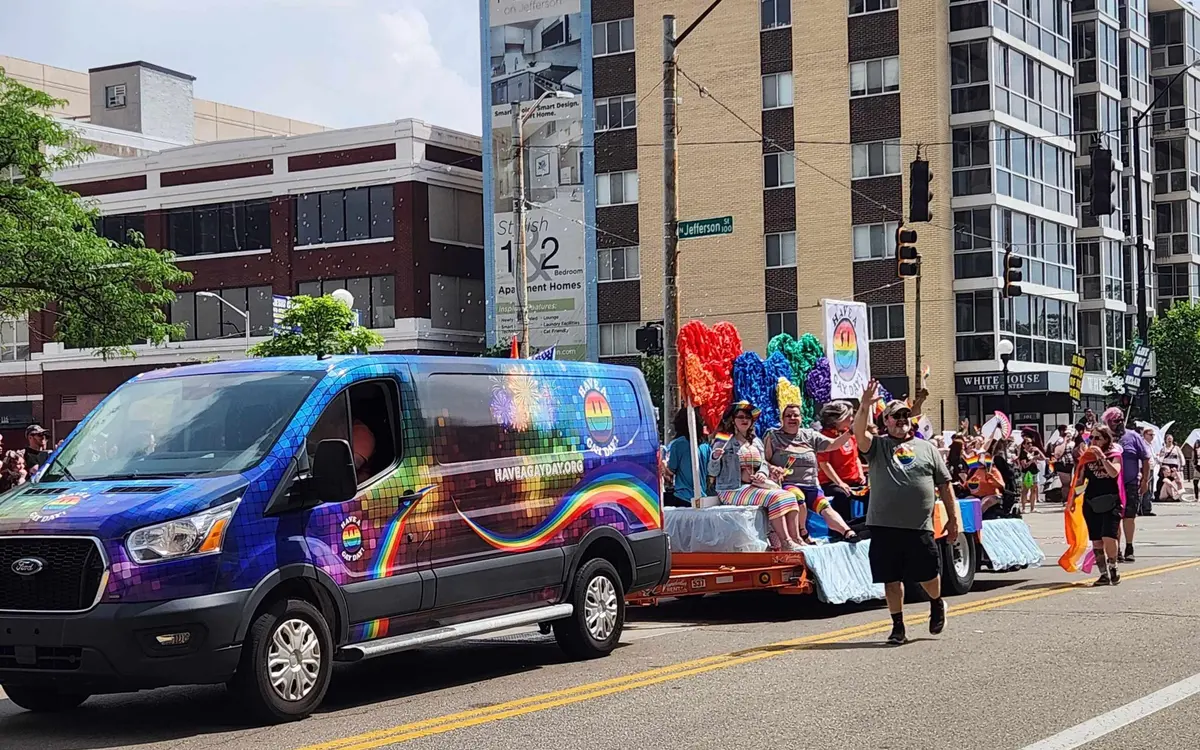 Have A Gay Day organization van and float participants waving to crowds along the Dayton Pride parade route