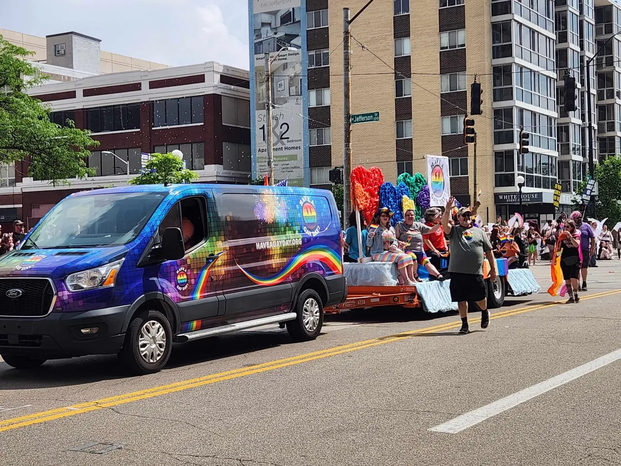 Have A Gay Day organization van and float participants waving to crowds along the Dayton Pride parade route