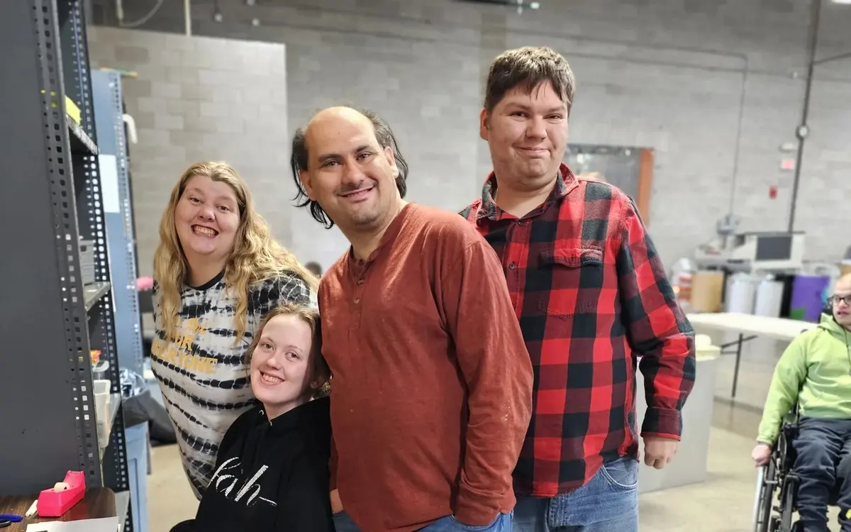 Adult day service participants smiling and posing together in the workshop room