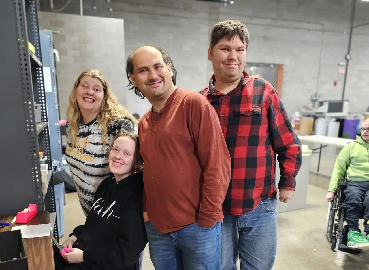 Adult day service participants smiling and posing together in the workshop room