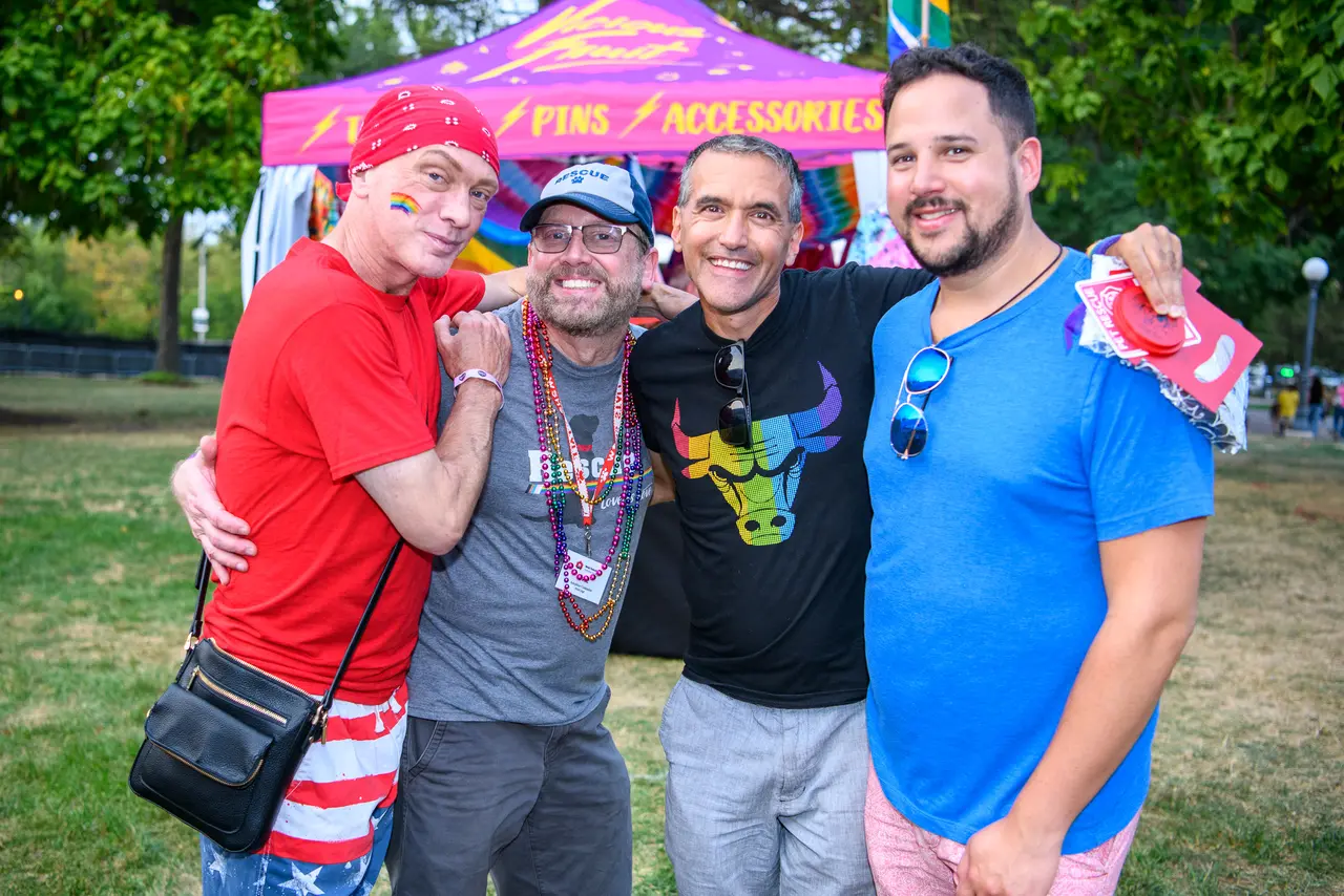 Four festival attendees smiling together at the Naper Pride outdoor festival