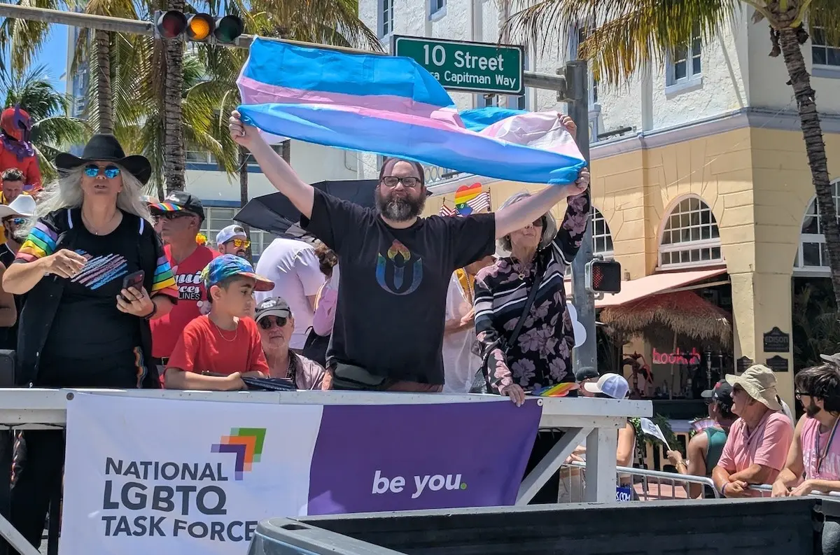 Task Force supporters riding a Pride parade float with a transgender flag and the Task Force banner