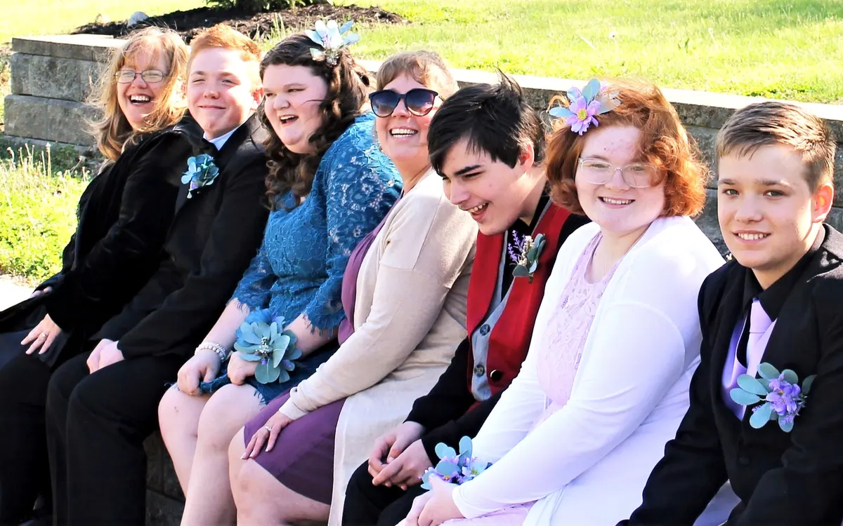 Group of participants and staff celebrating together outdoors in formal attire