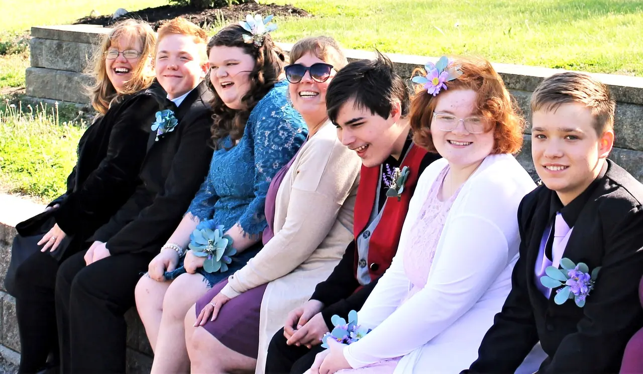 Group of participants and staff celebrating together outdoors in formal attire