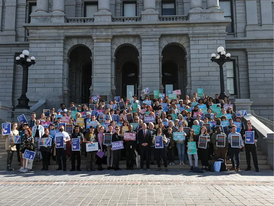 A large crowd of advocates holding signs on the steps of the Colorado State Capitol