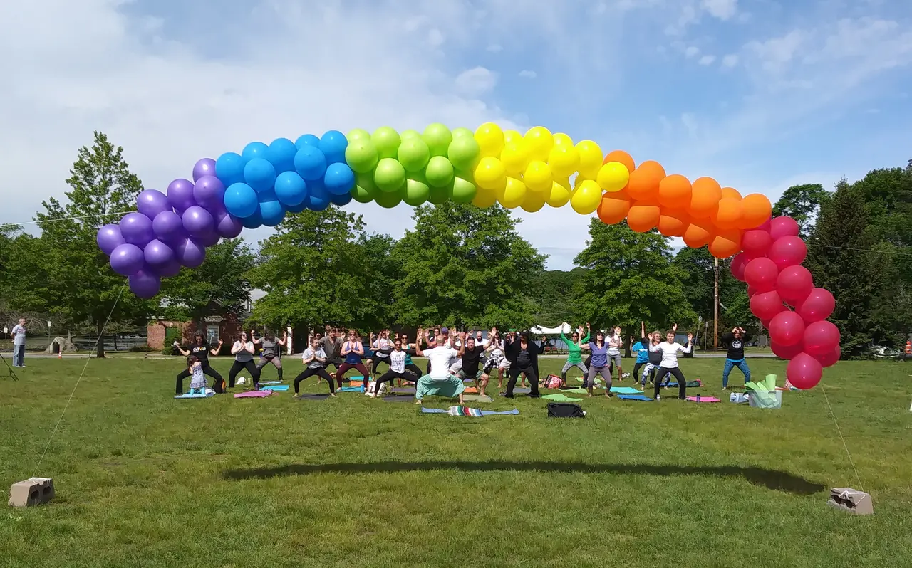 Community participants gathered outdoors on colorful mats for a South Coast Pride wellness session