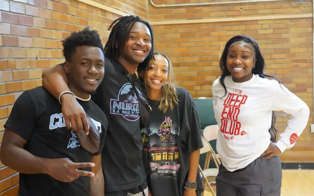 Four young adults smiling together at the community center
