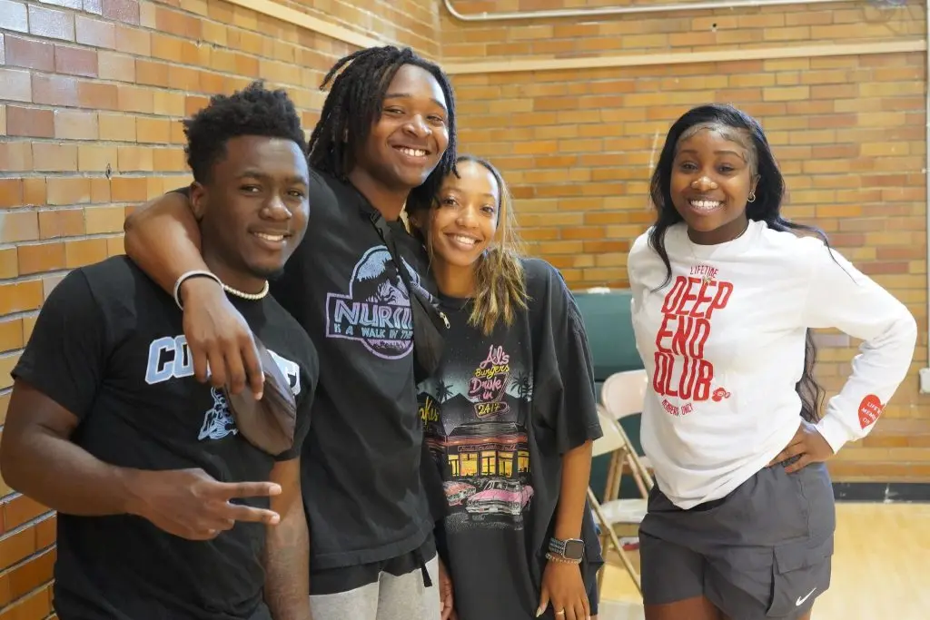 Four young adults smiling together at the community center