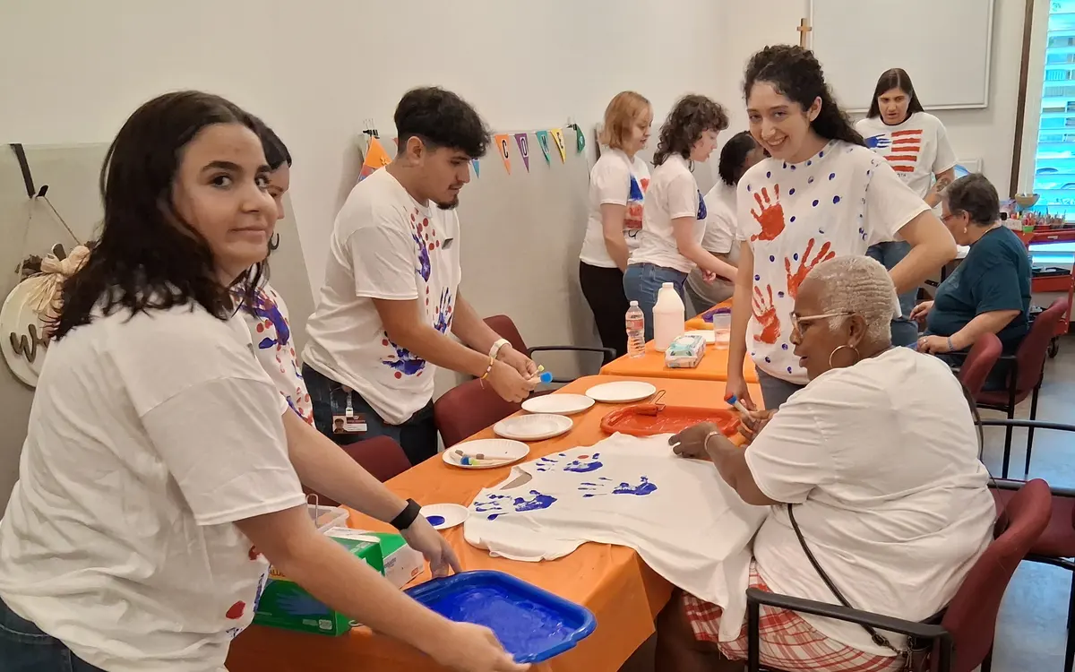 Self-advocates and volunteers painting t-shirts during a creative community workshop