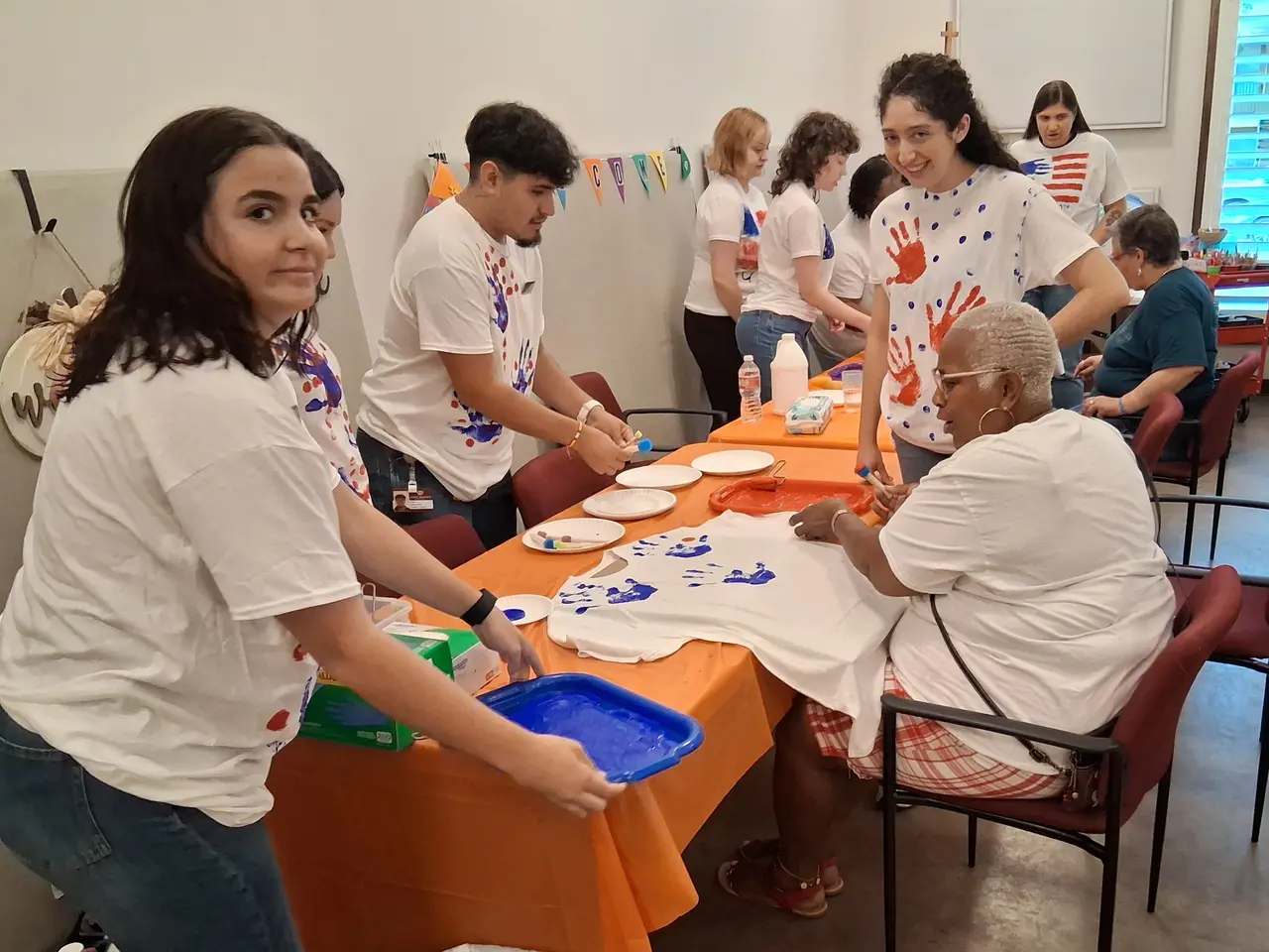 Self-advocates and volunteers painting t-shirts during a creative community workshop