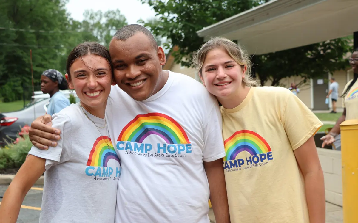 Campers and counselors smiling together in Camp Hope t-shirts at an outdoor summer activity