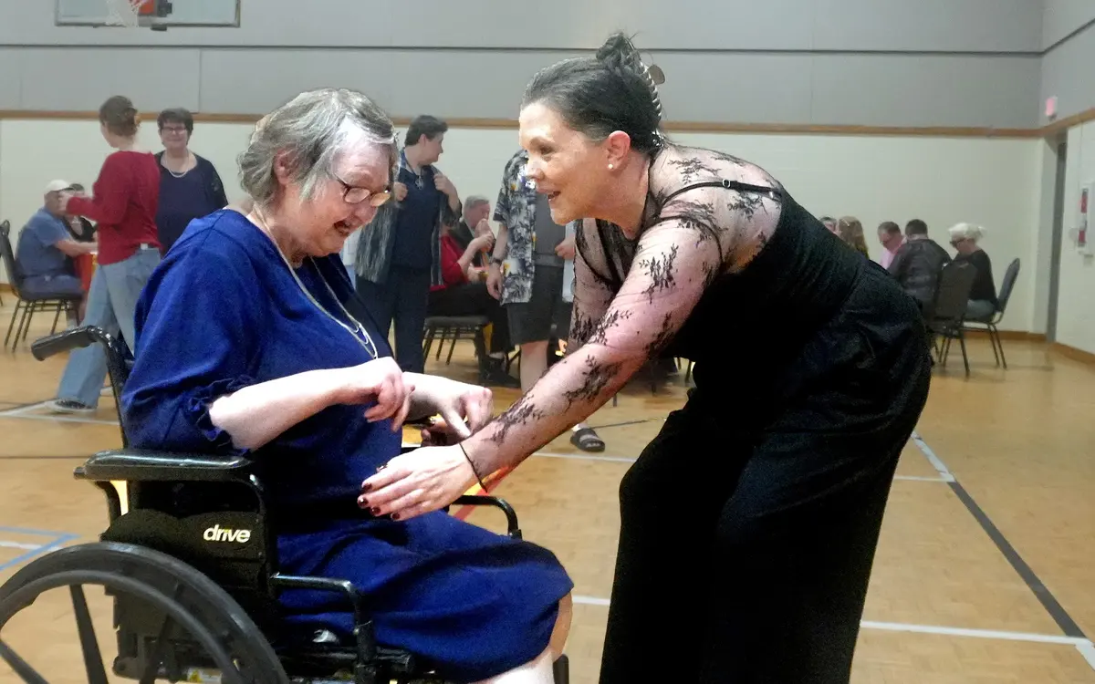 Participant in a wheelchair dancing with a partner at an Arc of Haywood County celebration