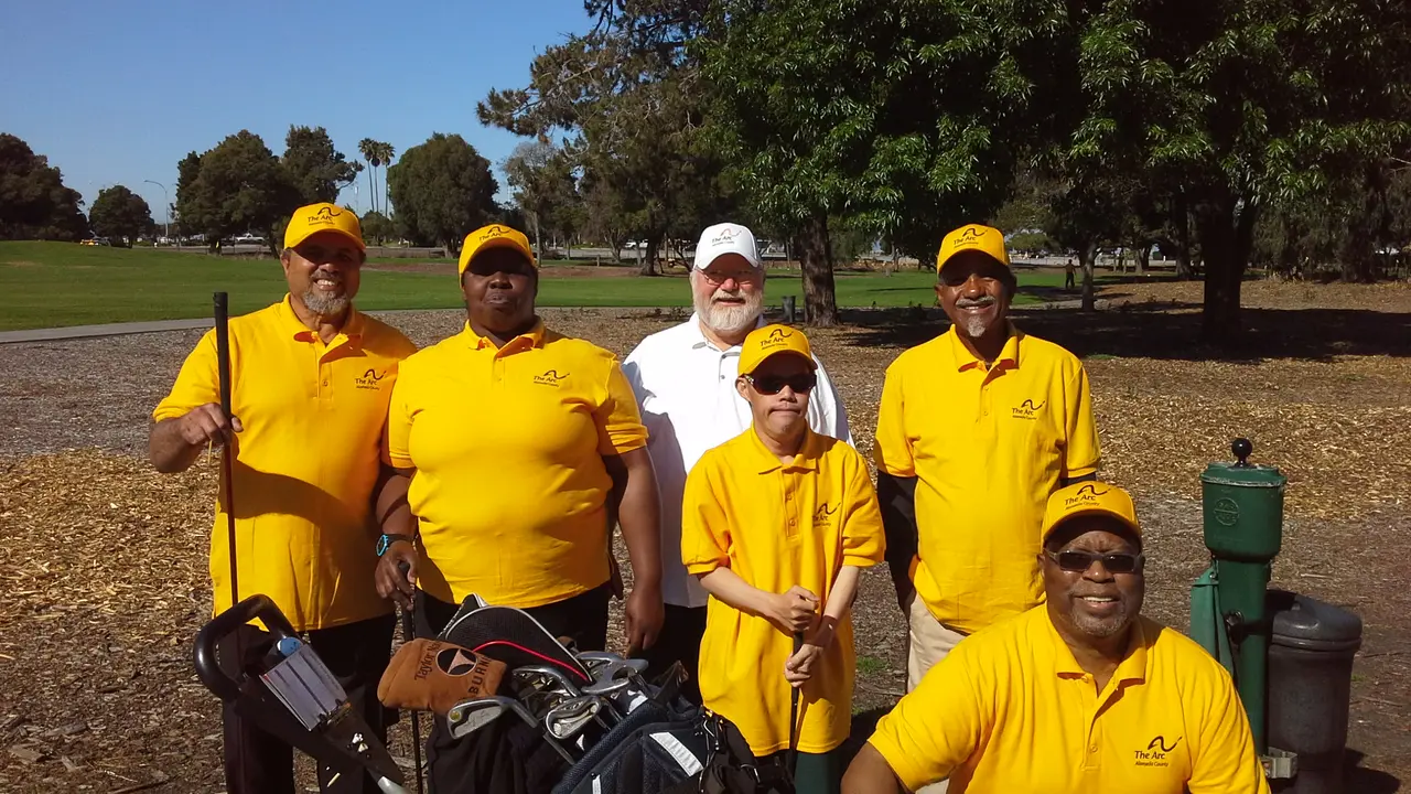 LifeLinks golf participants and volunteer coaches in yellow shirts on a golf course