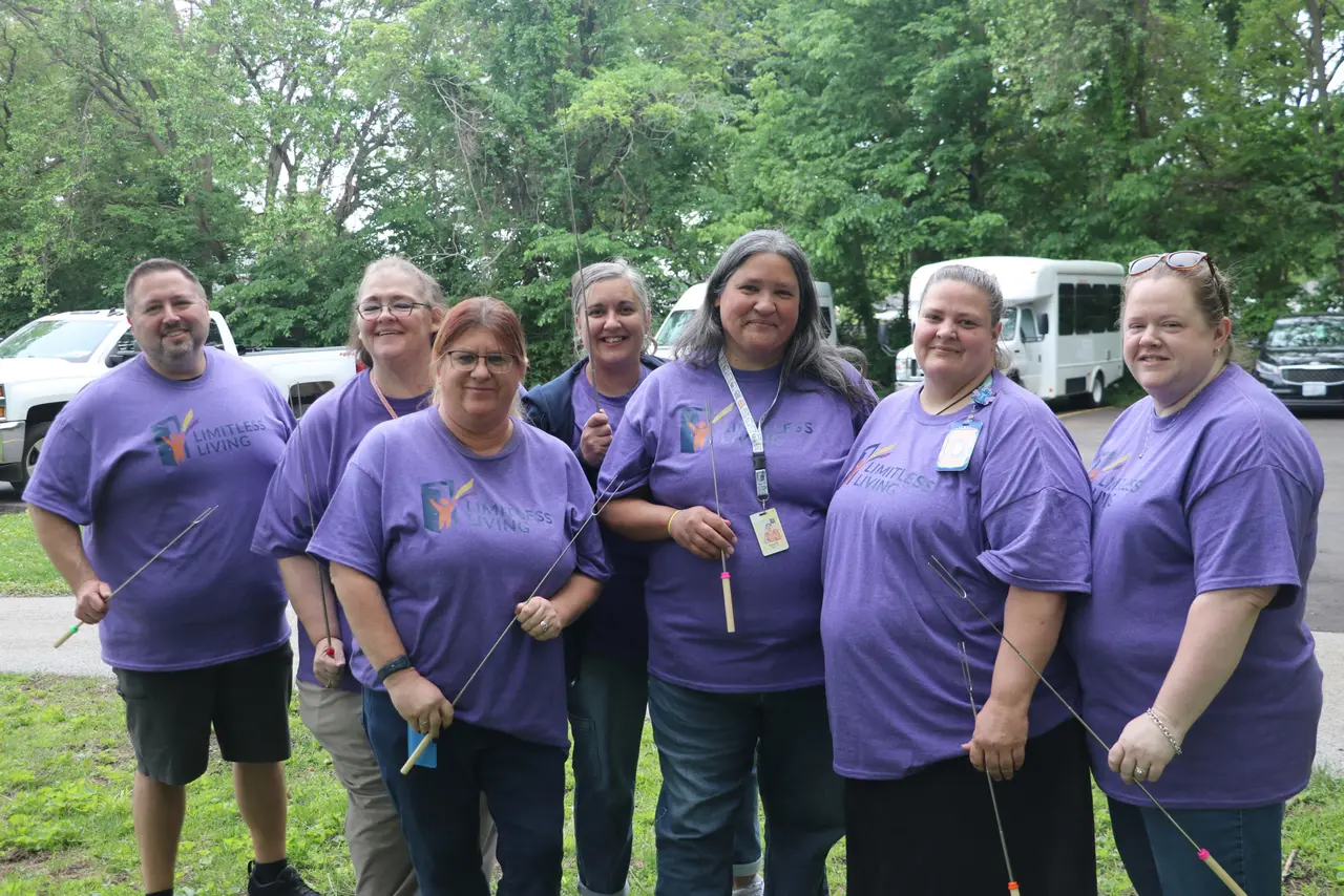 Participants and staff gathered outdoors by the organization shuttle van for a community outing