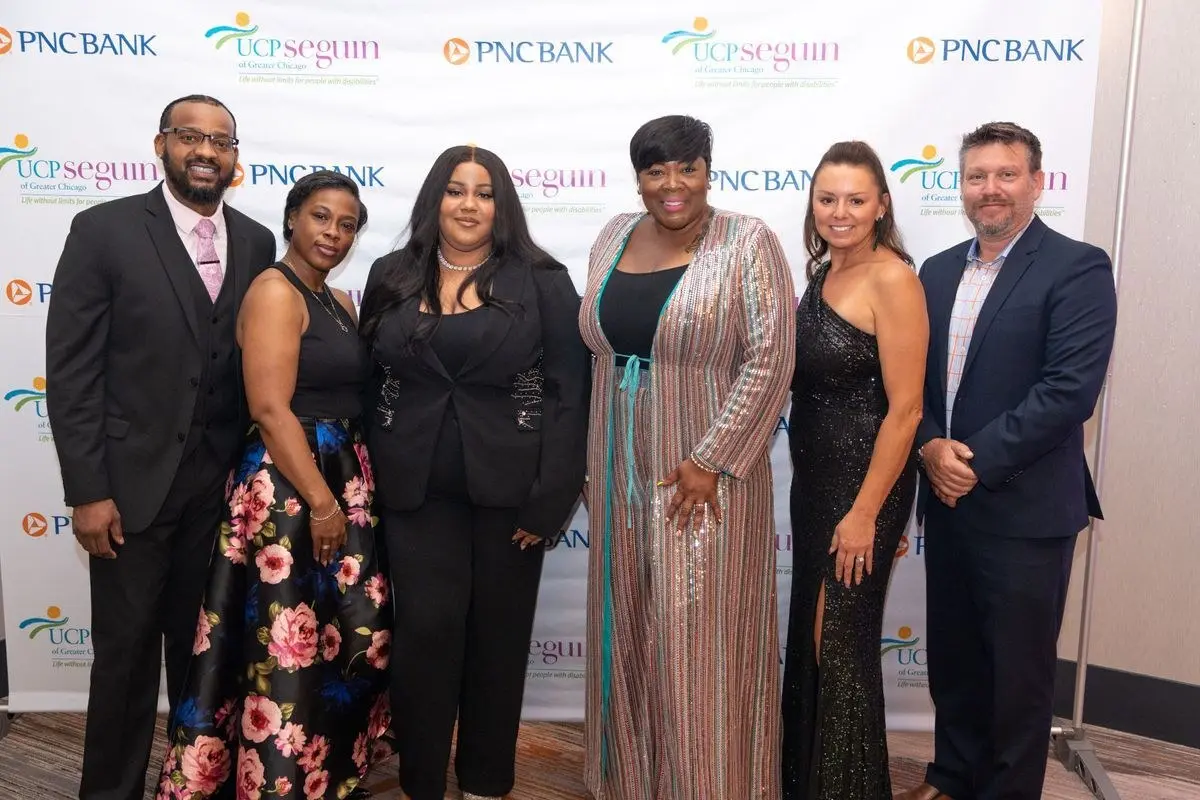 Six guests posing in front of a UCP Seguin backdrop at the Jazz, Joy and Generosity Gala