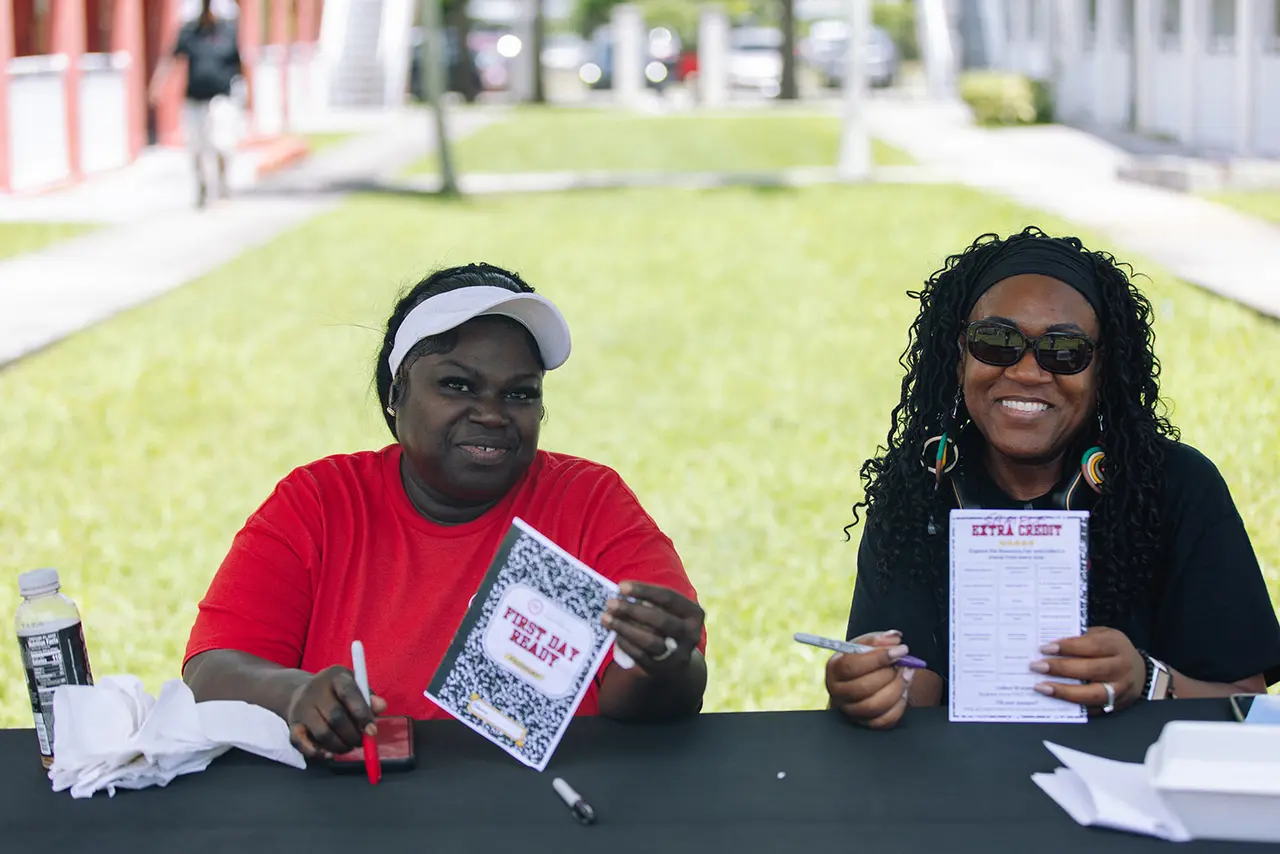 Two Urban League volunteers smiling at a registration table during First Day Ready