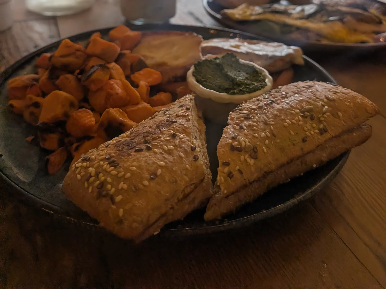 A plate at Green Zebra Cafe in Sarasota: roasted sweet potatoes, a seeded chicken pesto sandwich cut in half and a small pot of pesto