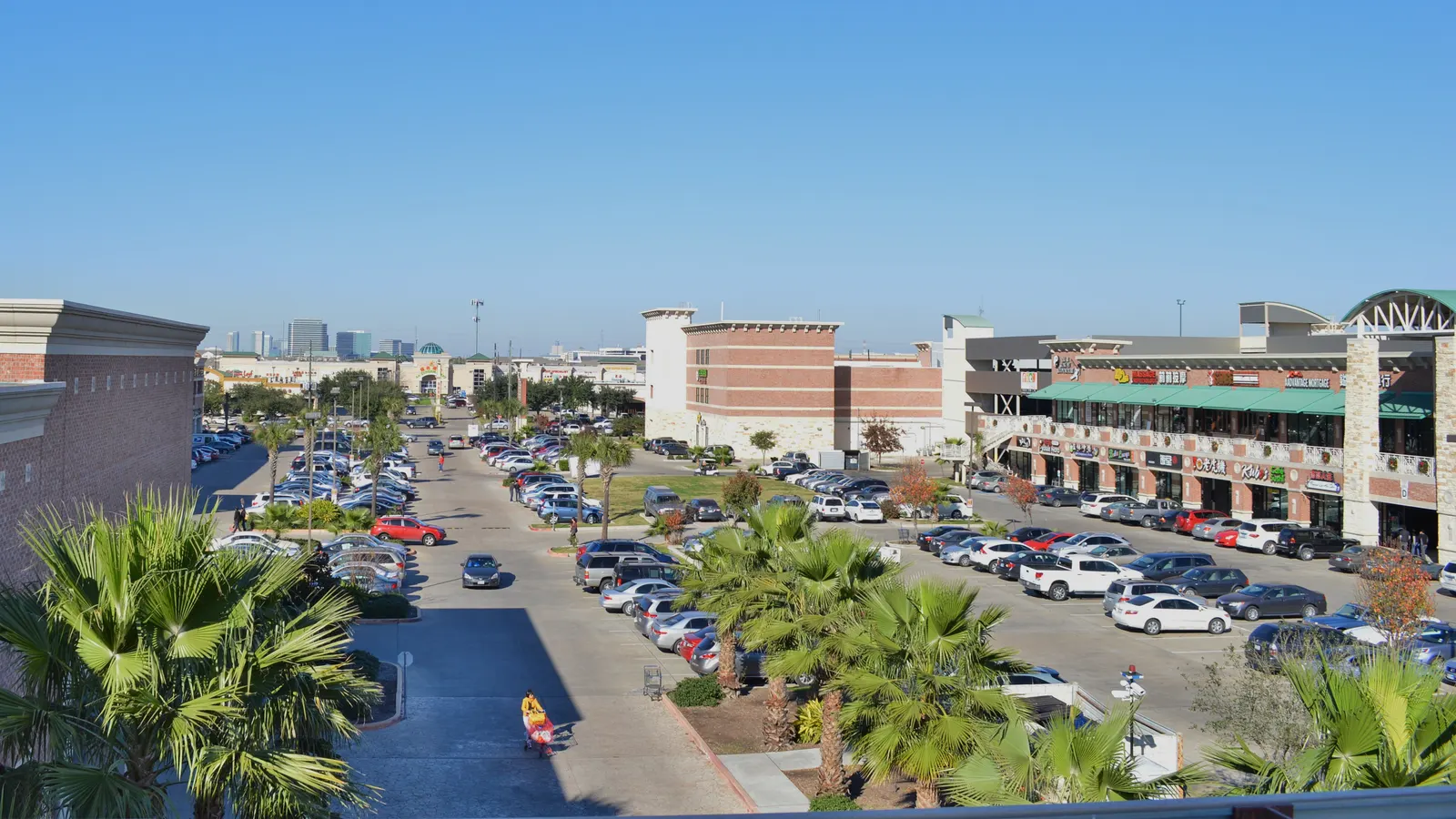 Parking lots and palm-lined shopping plazas in Houston's Chinatown along Bellaire Boulevard, seen from above
